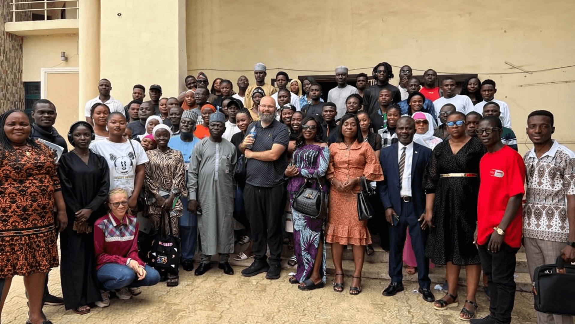 A large group of adults stand in a semi circle for a photograph