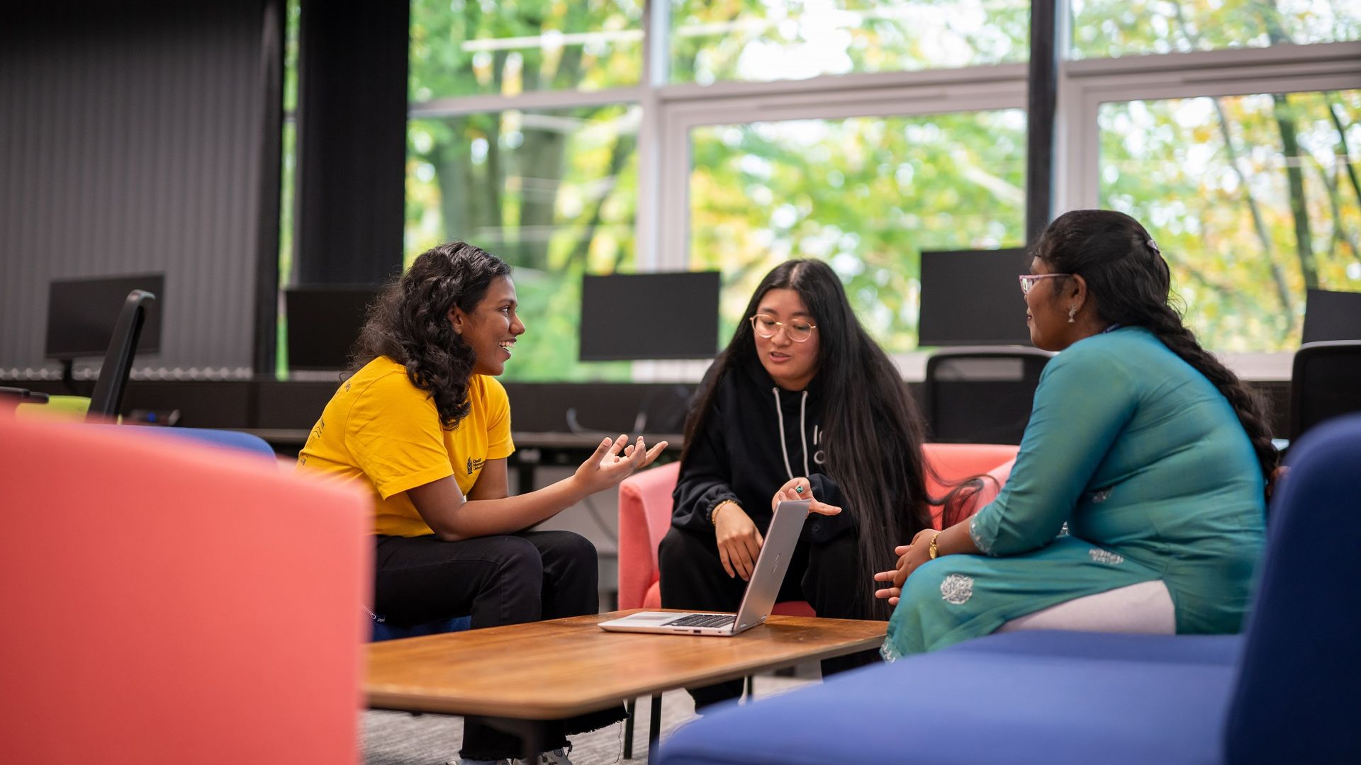 A group of three students sit around a low table for a chat