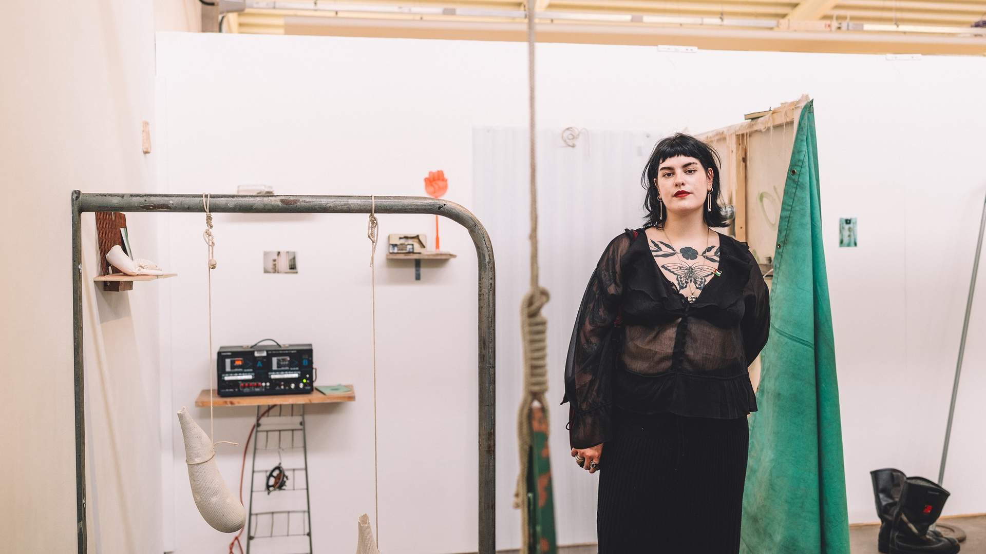 A young woman in black stands beside their art display
