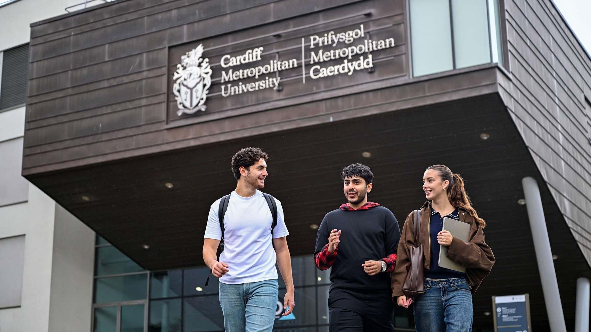 Three students walking and talking outside of the Cardiff School of Management