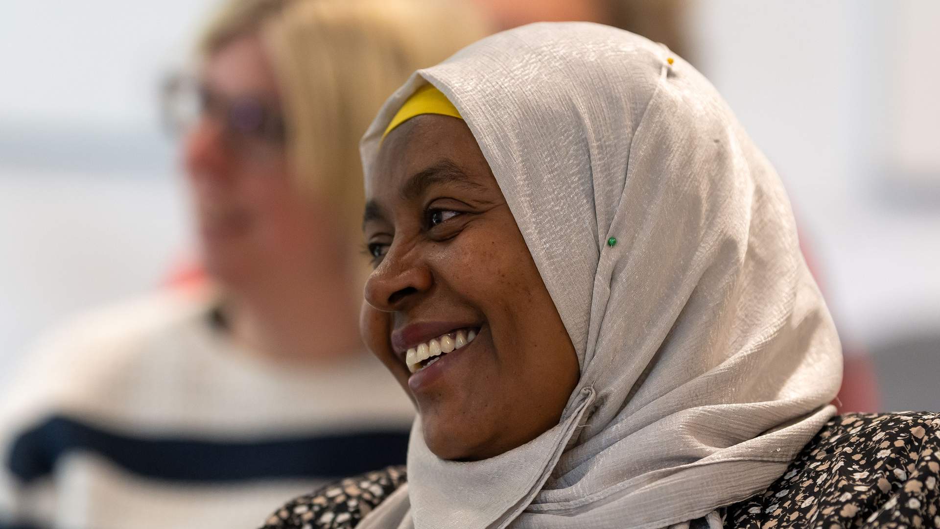 Adult woman in a white silver headscarf smiles