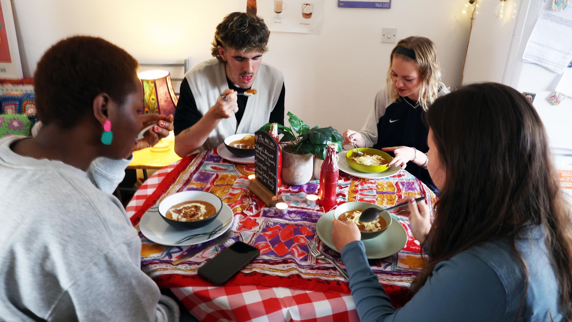 Cardfif Met students sit around a small dining table eating a bowl of soup each