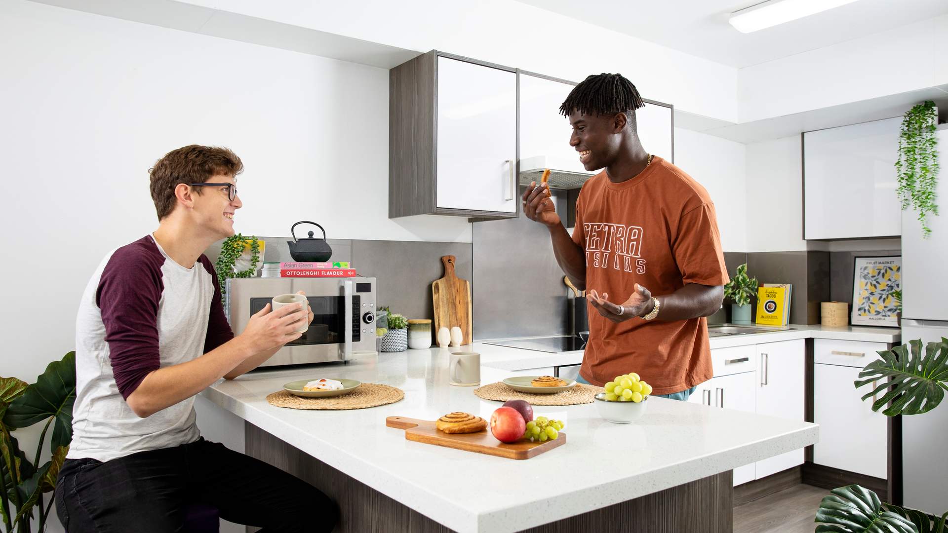 Two young men talk while eating at a kitchen counter island