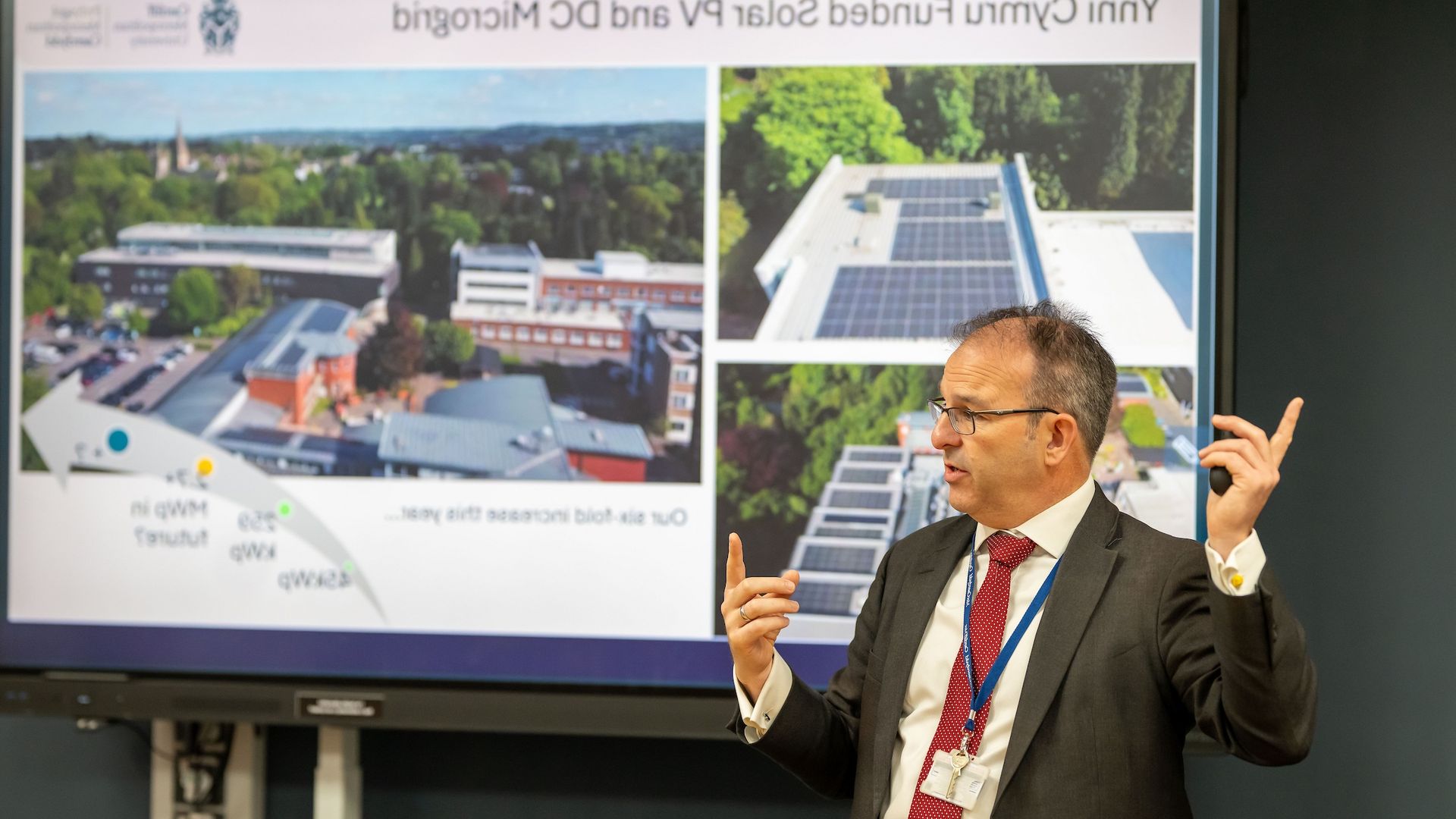 A member of Cardiff Met staff presents a presentation in front of a digital whiteboard
