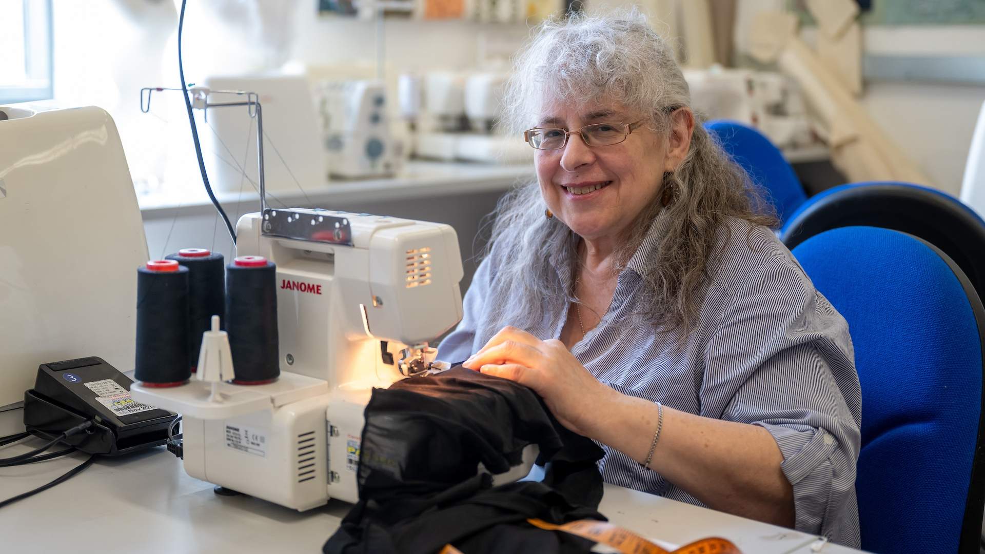 An elderly woman works at a sewing machine