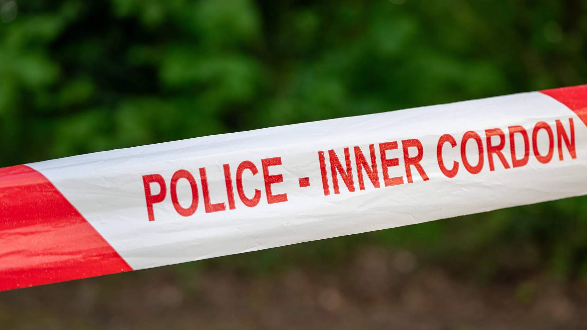 A close-up of police cordon tape. The letters on the tape read POLICE - INNER CORDON.