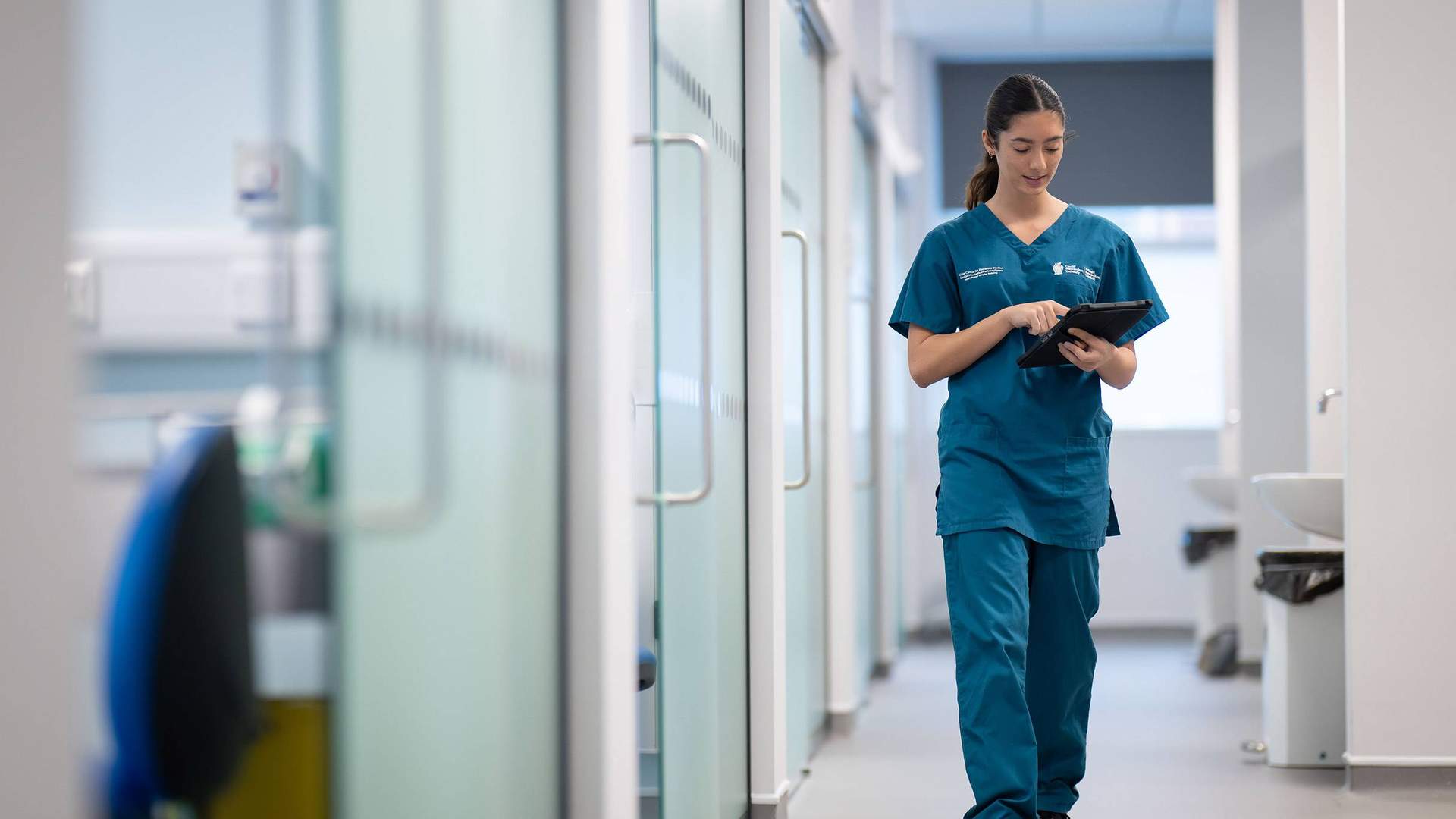 Student holding tablet while walking through Allied Clinical Health Hub