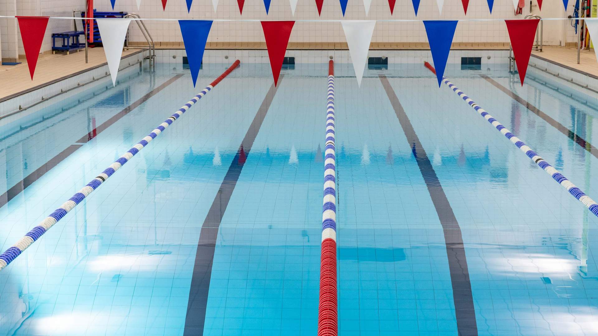 A swimming pool with race lanes and decorative bunting overhead