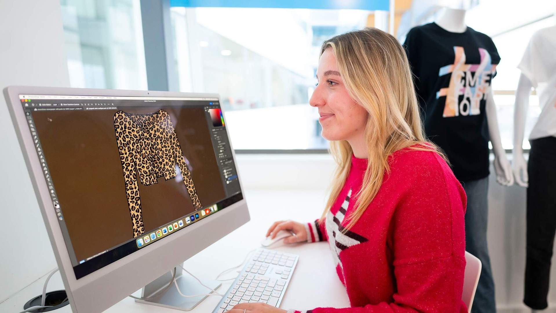 A person sat at a desk in front of a Mac computer.