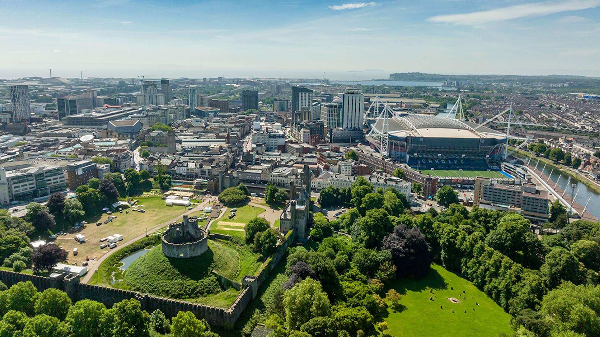 A city skyline featuring a large park in the foreground and a prominent building in the background.