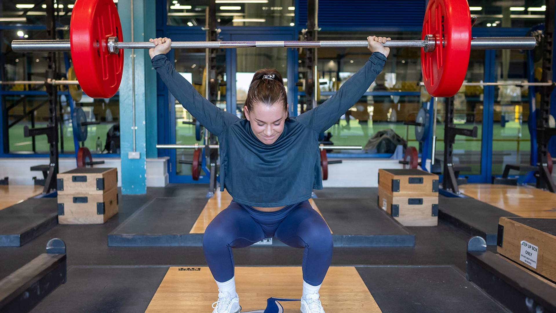 A woman executing a squat in a gym setting, highlighting her commitment to strength training and healthy living.