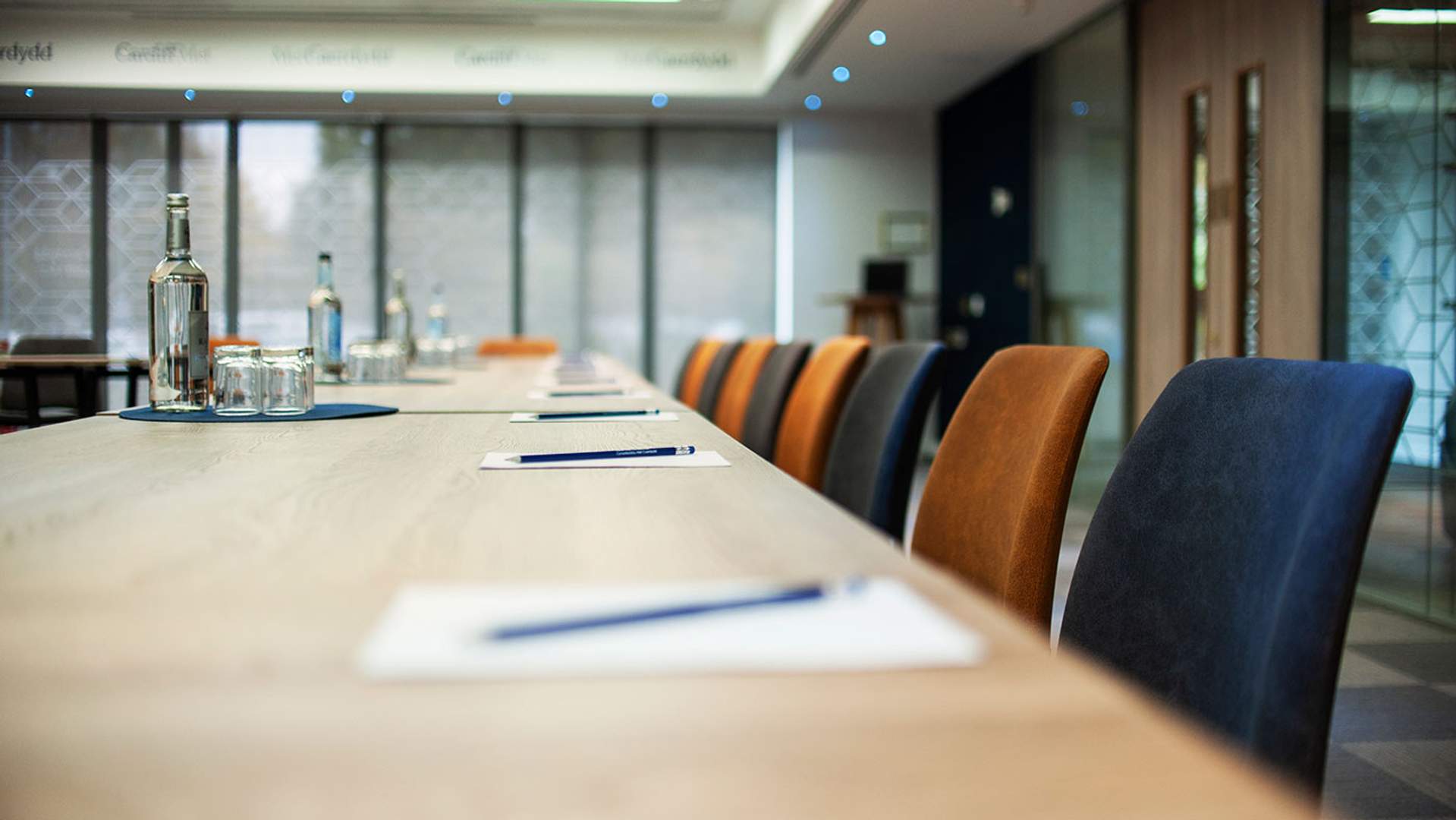 A conference table surrounded by chairs, featuring a bottle of water at the center, ready for a meeting.