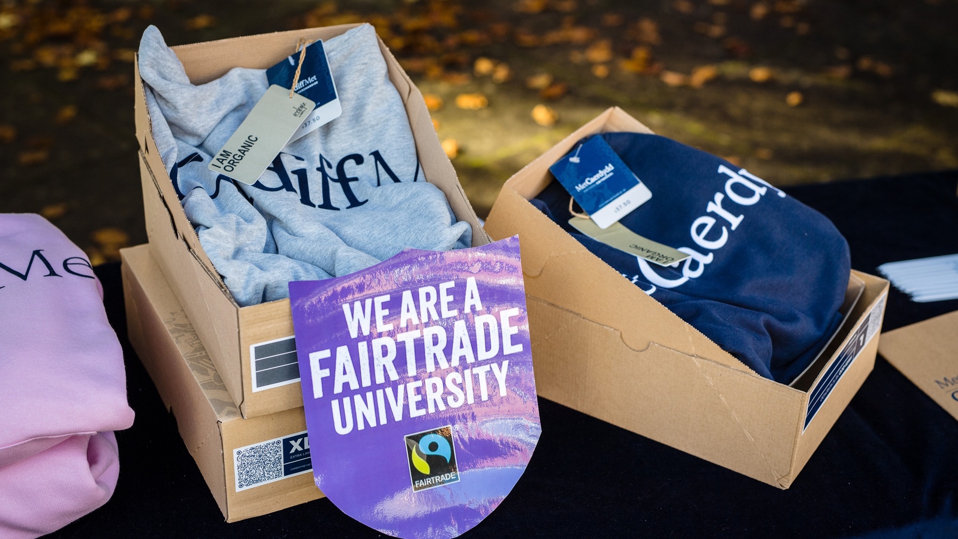 Cardiff Met-branded Fairtrade merchandise stacked in boxes alongside a 