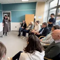 A woman stands before a group, confidently practicing in a choir.