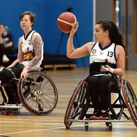 wo women in wheelchairs actively playing basketball, demonstrating skill and collaboration in a competitive setting.