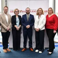 Several individuals gather in front of a colorful banner, showcasing camaraderie and a shared purpose.