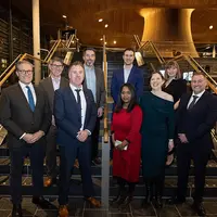 Several individuals gather on the stairs of a building, creating a lively atmosphere as they interact with one another.