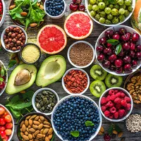 A colorful assortment of fruits and vegetables displayed in various bowls on a wooden surface.