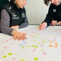 Two people sit at a table studying a flowchart.