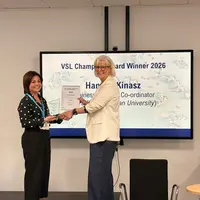 Hannah Kinasz recieving an award from a collegue in front of large monitor