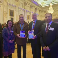 Four individuals stand in a room, proudly holding their awards, celebrating their achievements together.