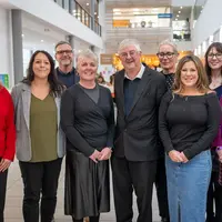 A group of diverse individuals standing together in a hallway, engaged in conversation.