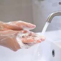 An individual washes their soapy hands under a running tap