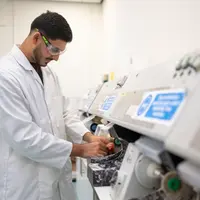A young adult in white laboratory uniform places his hands in a medical machine