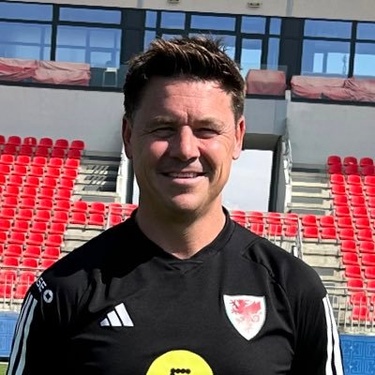 Mark Napieralla in a black shirt stands confidently in front of a stand in a large football stadium.No Staff Image