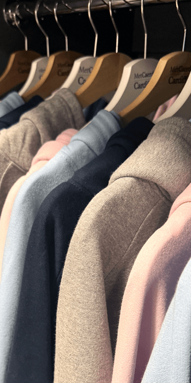A row of Cardiff Met-branded hoodies and sweatshirt lined up on a clothes rail
