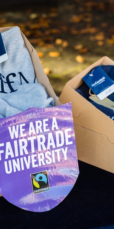 Cardiff Met-branded Fairtrade merchandise stacked in boxes alongside a 