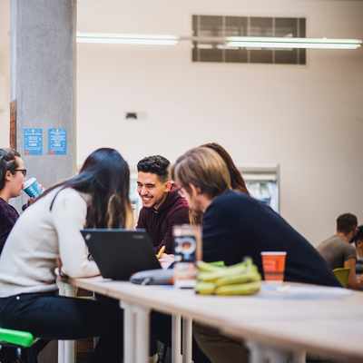 Five young adults sit around a table in an open cafe area
