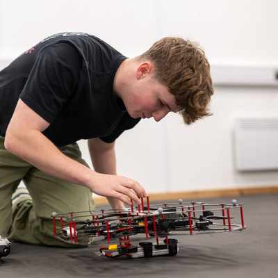 A student works with a small drone quadcopter.