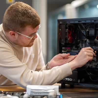 A woman wearing a polka dot jacket smiles while standing in front of a screen displaying a colorful line graph.