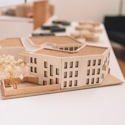 A replica office building made from wood sits on a white desk