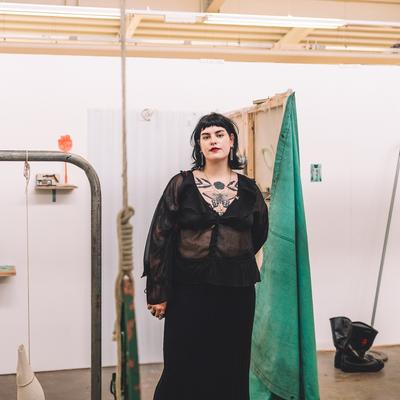 A young woman in black stands beside their art display