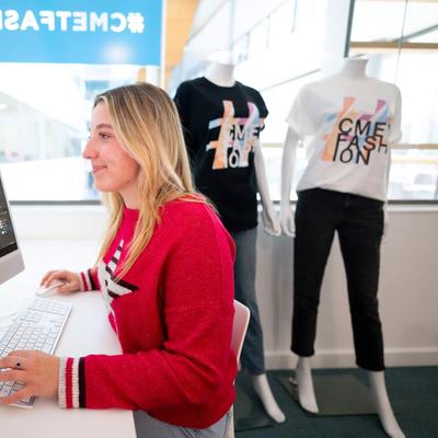 A person sat at a desk in front of a Mac computer.