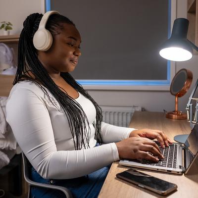 A woman wearing headphones sits at a desk, focused on her laptop, creating a productive work environment.