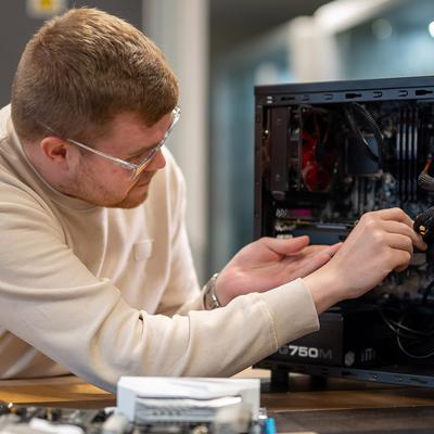 A woman wearing a polka dot jacket smiles while standing in front of a screen displaying a colourful line graph.