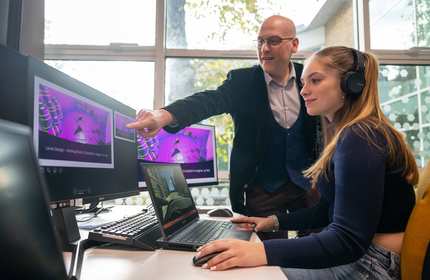 Lecturer and student using computer workstation