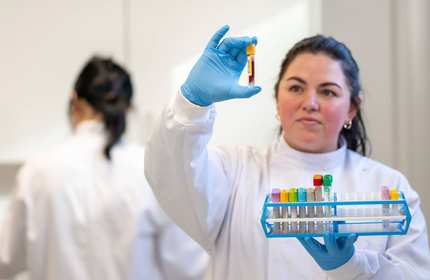 Student in laboratory coat holding test tube