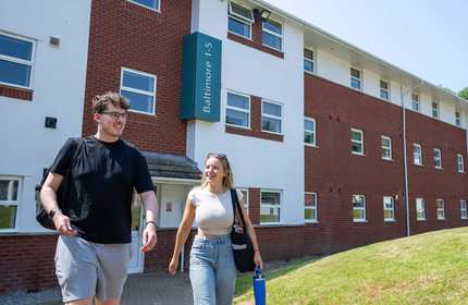 Two people walking together outside an accommodation block at Cardiff Met.