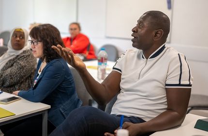 Adult sits at a desk in a classroom of adult learners