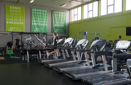 A young woman runs on a treadmill in an on-campus gymnasium