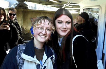 Two young people lean in to one another to pose for a photograph