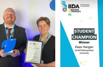 A man and woman stand side by side holding an award and framed certificate respectively
