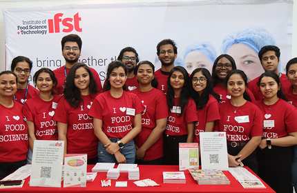 A group of individuals wearing red 'I heart food science' t-shirt stand in front of an Institute of Food Science Technology display