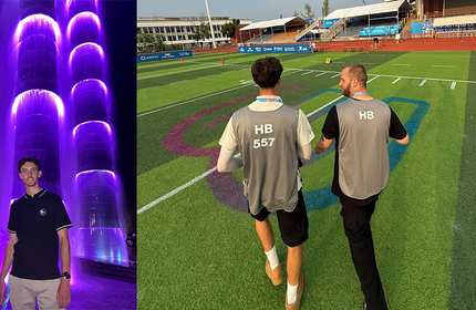 A young man stands in front of two large, lit waterfall towers / Two men walk walk across a sports field