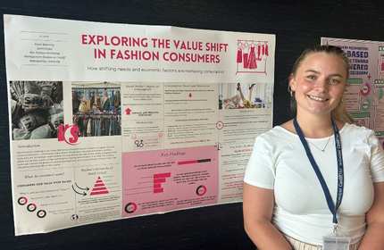 A young woman in a white t-shirt stands in front of an information display