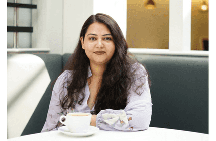 MSc Digital Marketing Management student sits at a table with a cup of coffee